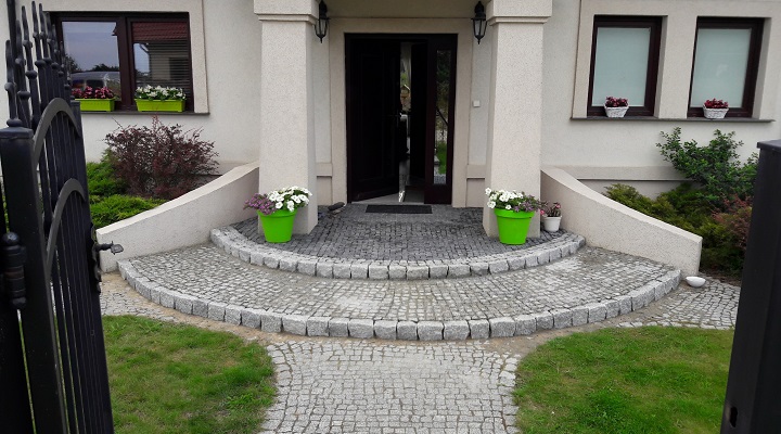 Wejście do domu z półokrągłymi schodami z kostki granitowej – elegancka nawierzchnia brukowa w ogrodzie