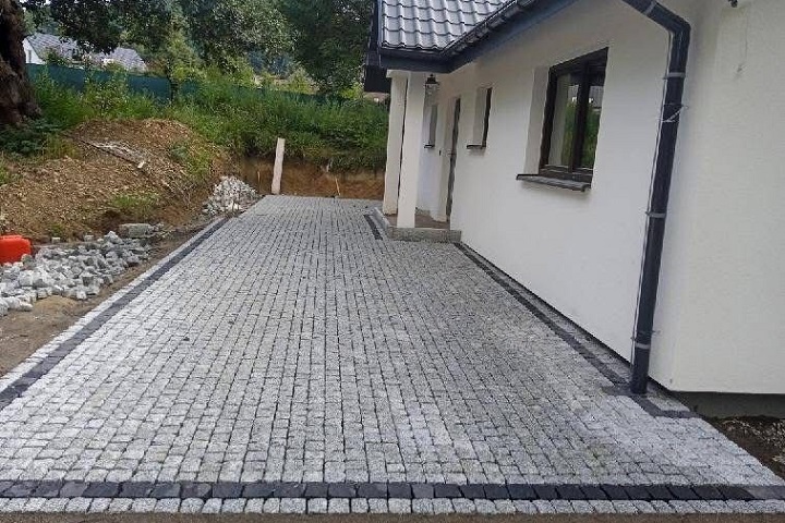 Układanie kostki granitowej z naturalnego kamienia granitowego przed wejściem głównym do domu
